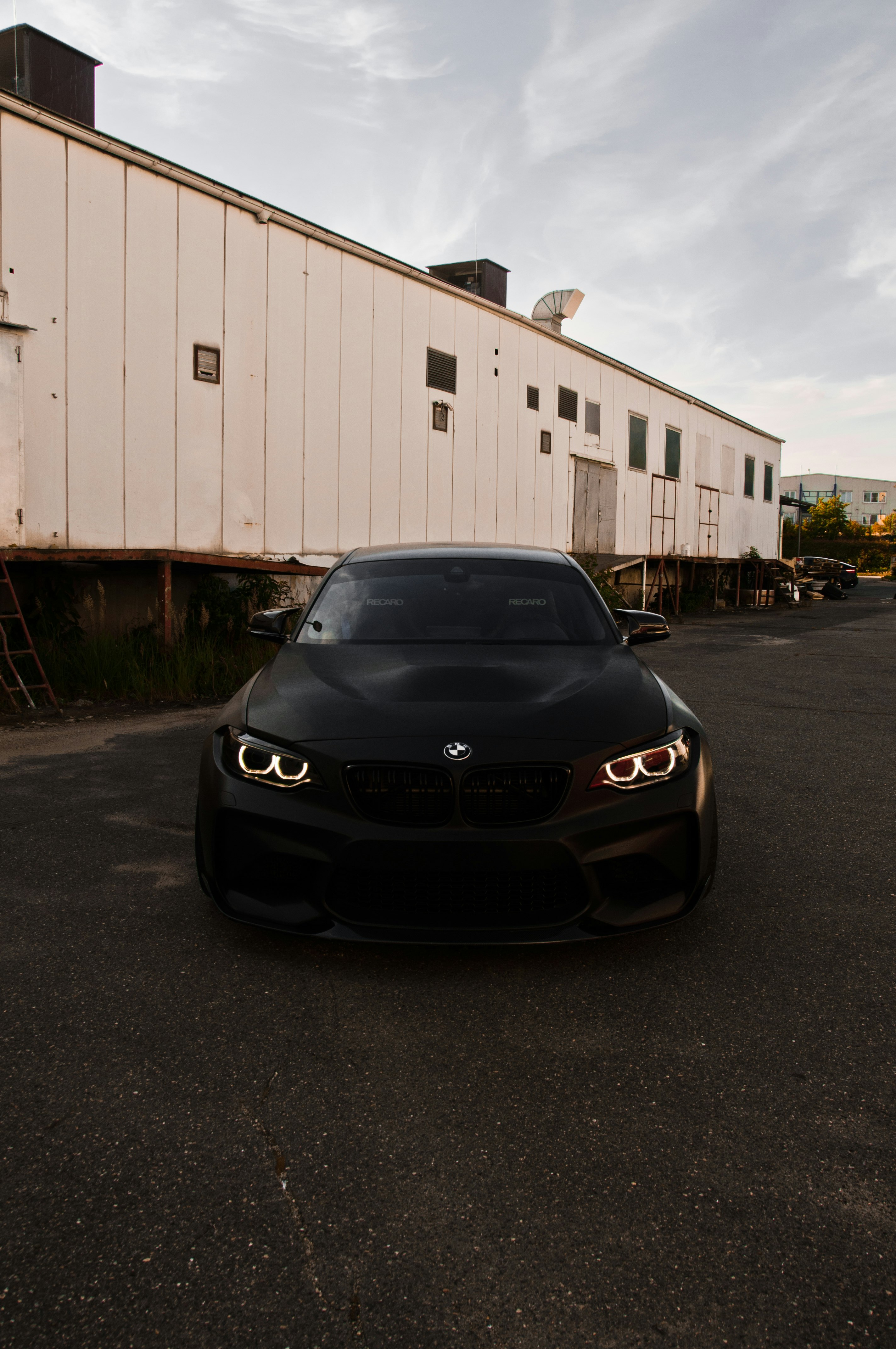 black bmw car parked near white garage during daytime